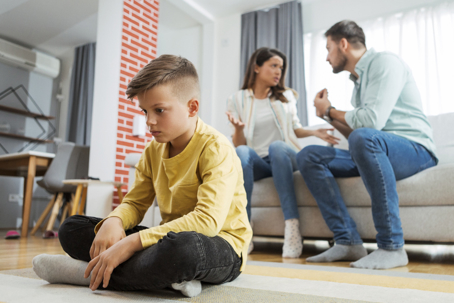 sad child with parents arguing behind him
